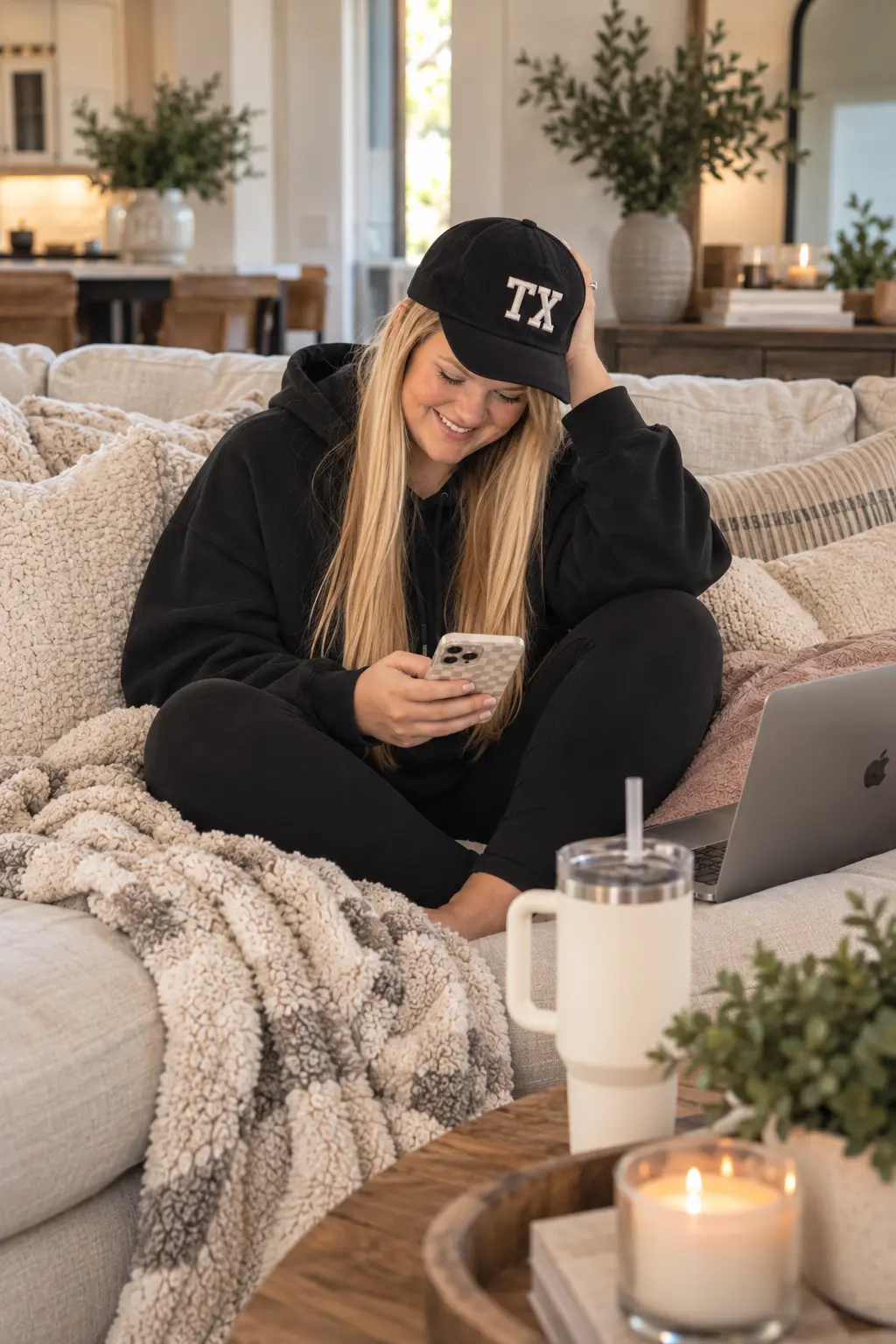 Kendyll in black loungewear on the couch, working from her phone